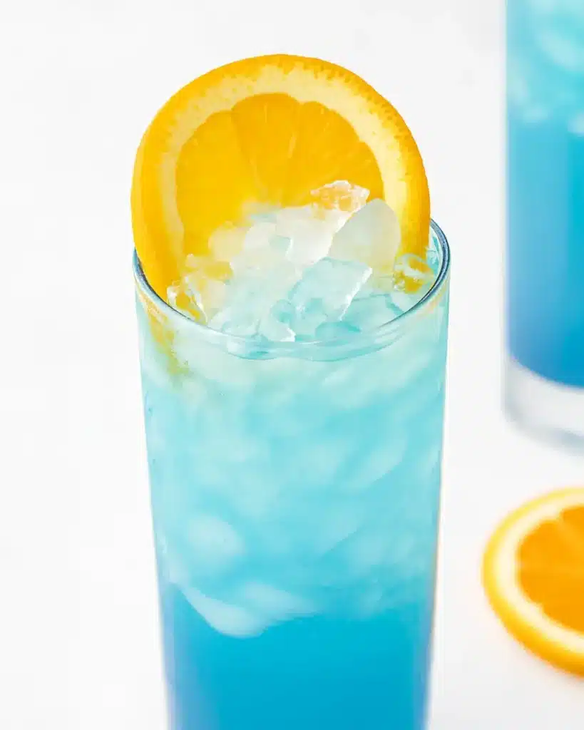 Blue Lagoon Spritzer Recipe: Fizzy, Citrus, and So Refreshing Blue Lagoon Spritzer Blue Lagoon Spritzer in a tall glass with lemon garnish