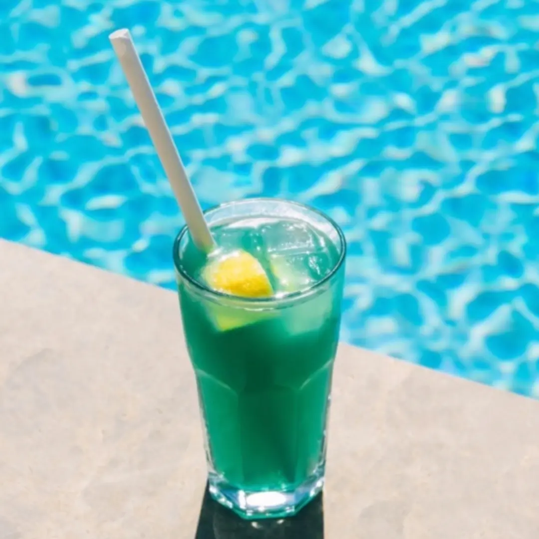 Liquid Marijuana cocktail by the pool with lemon garnish and straw
