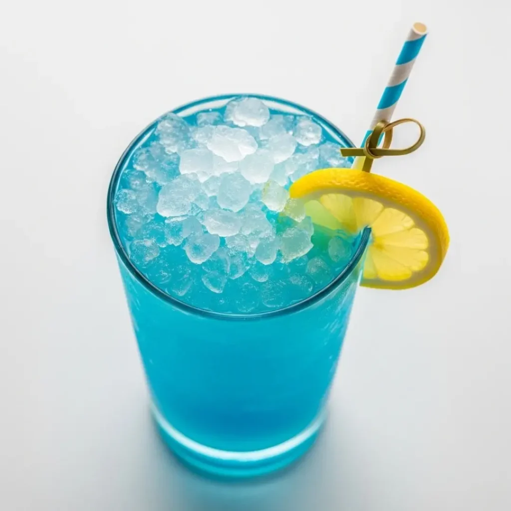 A vibrant blue lagoon cocktail in a clear glass with lemon garnish
