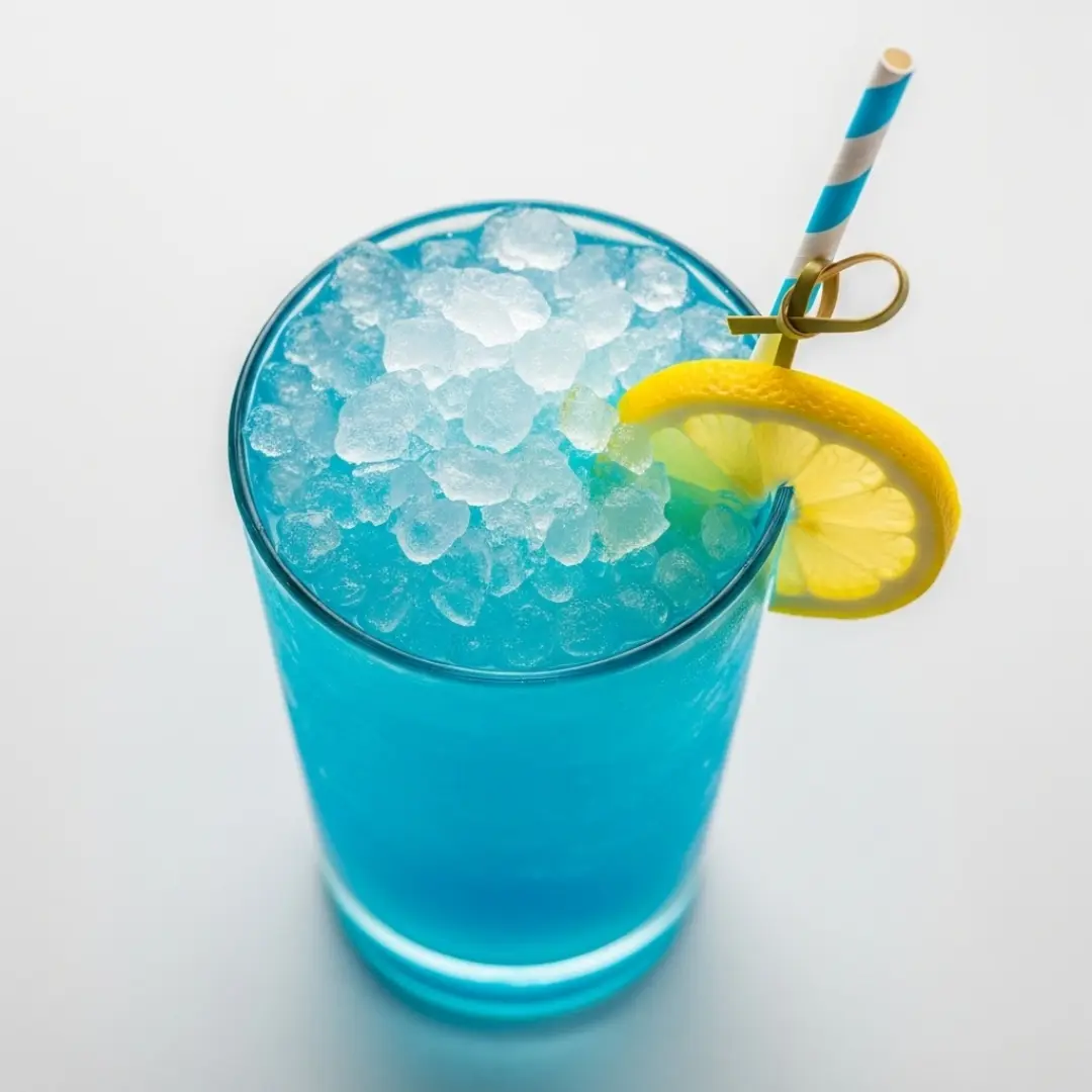 A vibrant blue lagoon cocktail in a clear glass with lemon garnish
