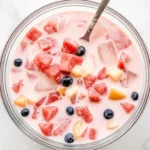 Bowl of creamy Filipino fruit salad punch with ice cubes and fresh berries