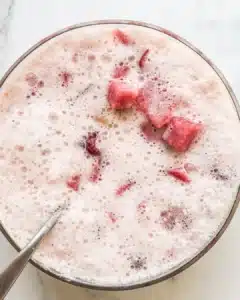 Frothed pink strawberry punch with watermelon and berries floating on top