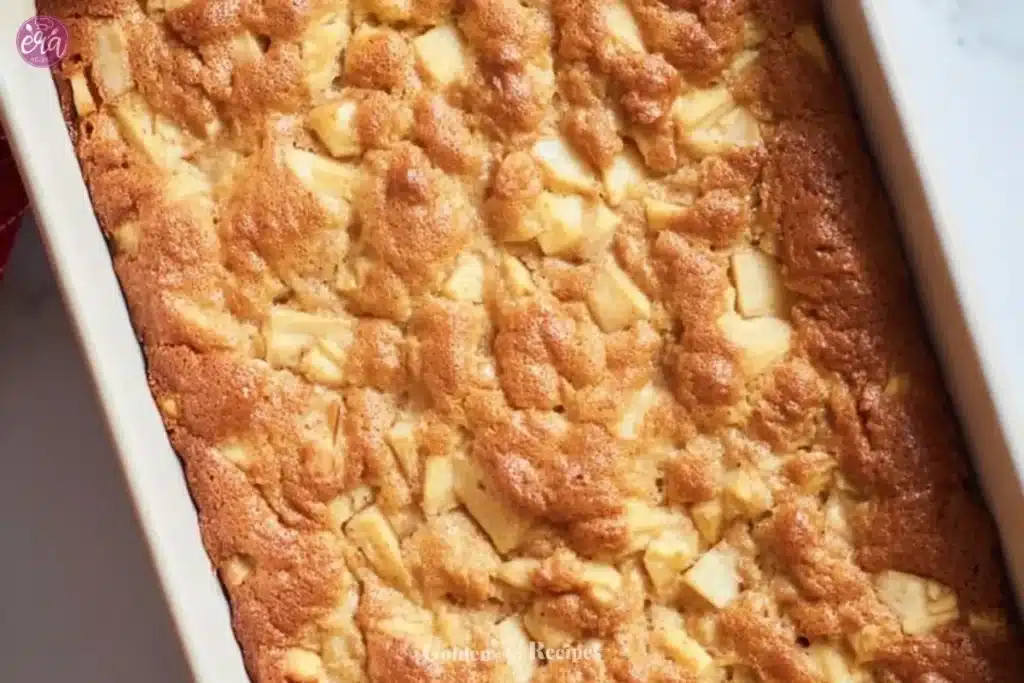 Amish Apple Cake 1 A slice of delicious Amish Apple Cake on a white plate with apples in the background