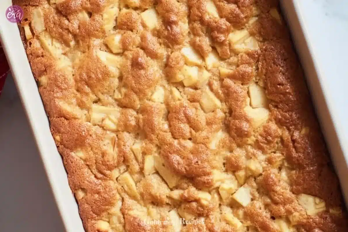 A slice of delicious Amish Apple Cake on a white plate with apples in the background