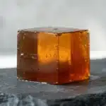 A close-up of a firm, amber-colored gelatin cube showing the density required for satiety.