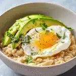 Bowl of savory avocado oatmeal topped with herbs and spices