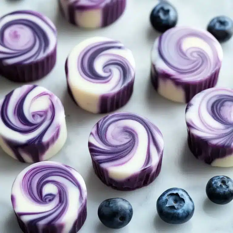 Blueberry swirl yogurt bites stacked on a white plate with blueberries