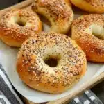 Homemade Greek Yogurt Bagels topped with sesame seeds on a baking tray