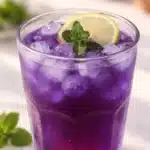 A cup of butterfly pea tea with dried flowers, showcasing its vibrant blue color.