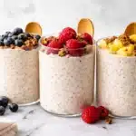 Delicious bowl of kefir overnight oats topped with colorful frozen fruit.