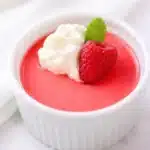 A spoon slicing through chocolate protein jello dessert on a white plate.