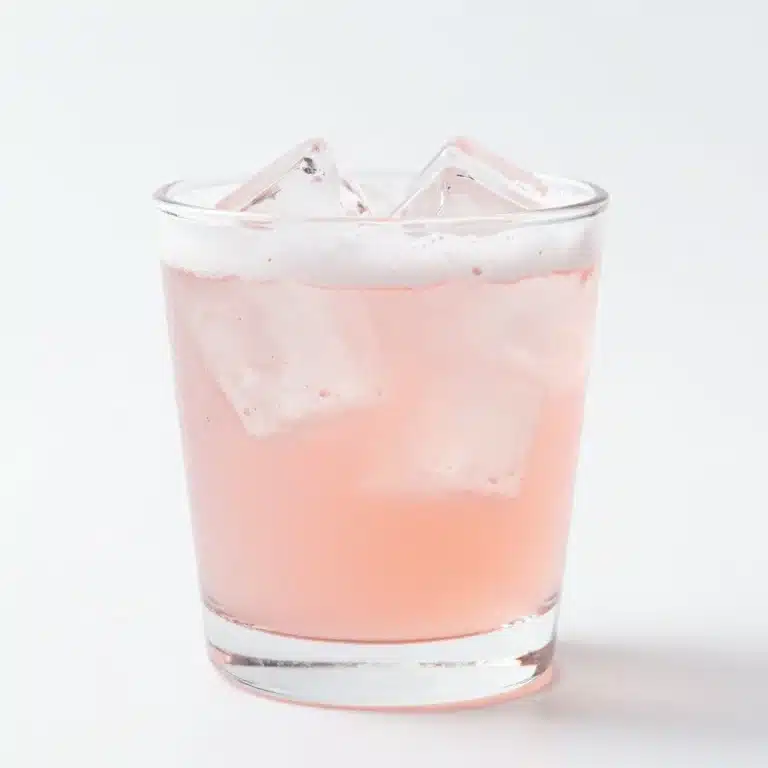 A glass of homemade rhubarb soda garnished with fresh rhubarb and ice.