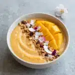Iced Mango Lassi Smoothie Bowl topped with fruits and nuts