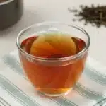 A cup of herbal nettle infusion with fresh nettle leaves.