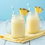 Refreshing Orange, Pineapple & Coconut Mocktail in a glass with tropical garnishes.