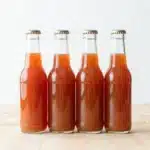 A bottle of Rhubarb Schnapps surrounded by fresh rhubarb and elegant glasses.