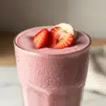 Delicious Strawberry Banana Smoothie in a glass with fresh strawberries and bananas.
