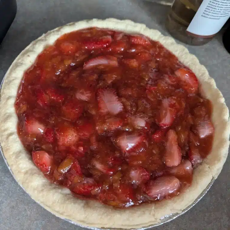 Delicious homemade Strawberry Rhubarb Pie topped with fresh strawberries and flaky crust.