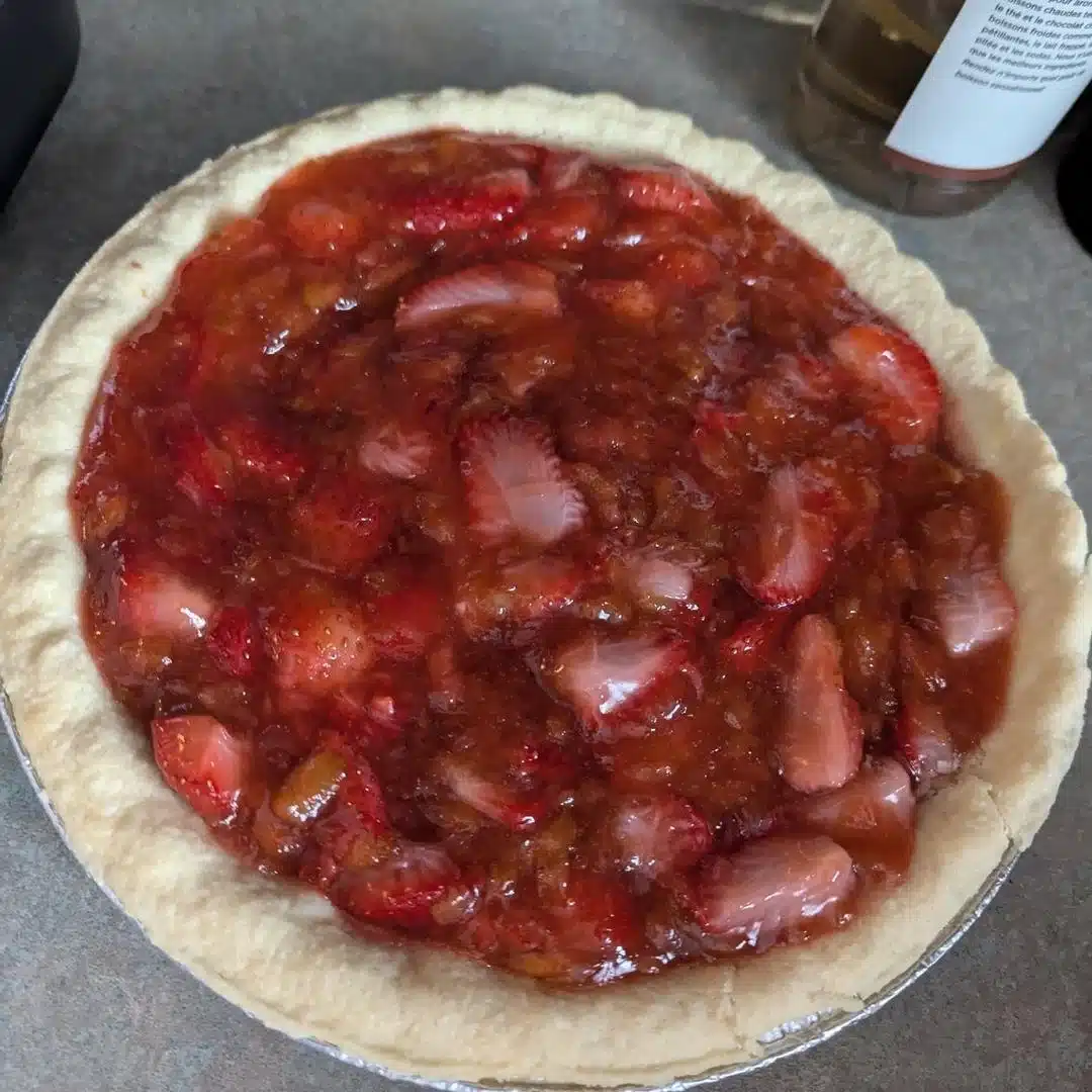Delicious homemade Strawberry Rhubarb Pie topped with fresh strawberries and flaky crust.