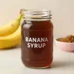 Delicate banana simple syrup recipe ingredients and finished syrup in glass jar.