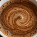A steaming cup of Cinnamon Coffee garnished with a cinnamon stick