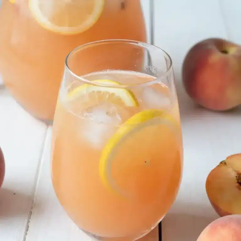 Glass of Ginger Peach Lemonade Enchanted Heart with peach slices and ginger garnish.