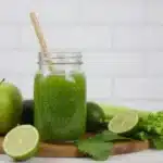 Fresh green juice in a glass with fruits and vegetables for beginners