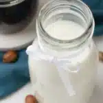 Homemade hazelnut coffee creamer in a glass jar on a kitchen counter.