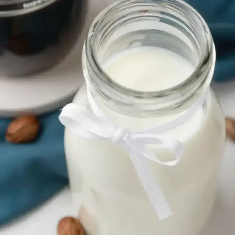 Homemade hazelnut coffee creamer in a glass jar on a kitchen counter.