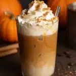 Iced Pumpkin Spiced Latte in a glass with whipped cream and spices