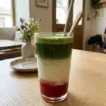 Strawberry Matcha Latte in a glass with fresh strawberries and matcha powder
