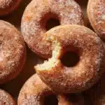 Close-up of cinnamon sugar-dusted apple cider donuts on a plate.